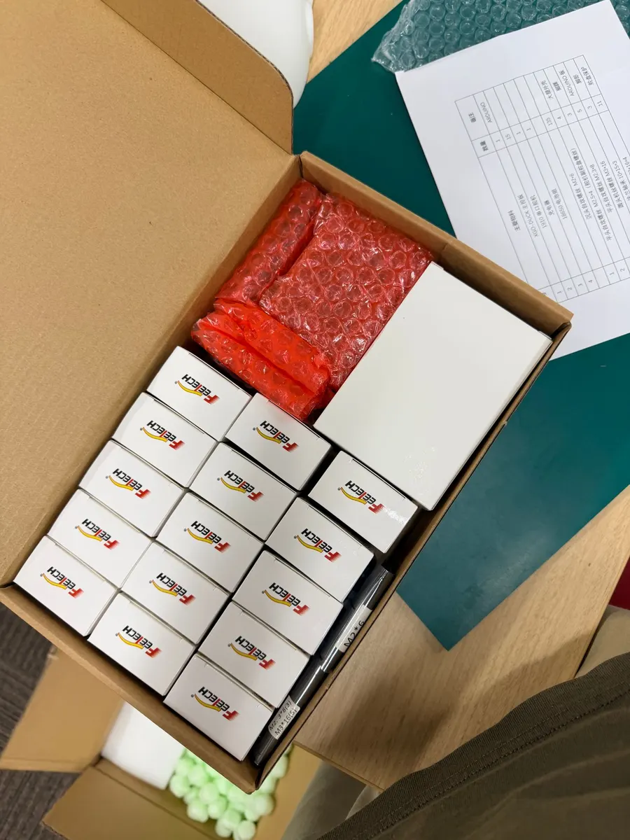 段ボール箱に並んだ Feetech サーボの箱と、部品表
